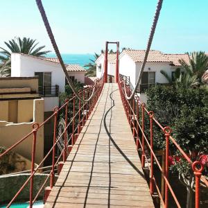 un puente colgante sobre una piscina frente a una casa en Hotel Festival Plaza Playas Rosarito, en Rosarito