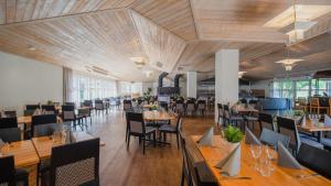 a restaurant with wooden ceilings and tables and chairs at Hotell Erikslund in Ängelholm
