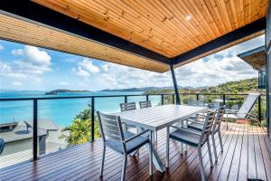 a table and chairs on a deck with a view of the ocean at Shorelines in Hamilton Island