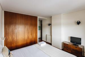 um quarto com uma cama com um armário de madeira e uma televisão em Riverfront Haven Family's Choice with Free Garage em Porto