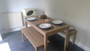 una mesa de madera con platos y una TV. en Cosy house for business travel and pleasure, en Bickershaw