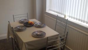 a table with plates and a bowl of fruit on it at Delightful house with big ambitions in Leigh