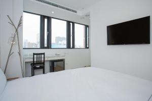 a living room with a tv and a desk with a chair at Mini West Hotel in Taichung