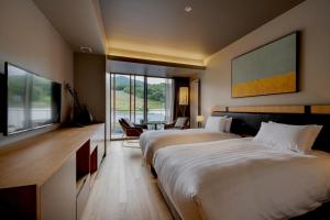 a hotel room with two beds and a desk and a table at Fenix Furano in Furano