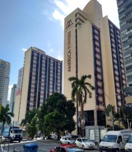 a large building with cars parked in a city at Flat Athenas 611 in Salvador