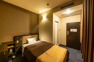 a hotel room with a bed and a door at Kyoto Central Inn in Kyoto
