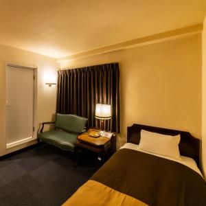 a hotel room with a bed and a green chair at Kyoto Central Inn in Kyoto