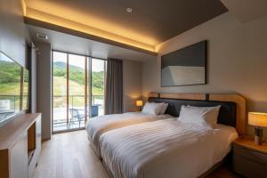 a bedroom with a large bed and a large window at Fenix Furano in Furano
