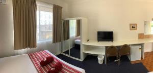a hotel room with a bed and a desk with a television at Panorama Motor Inn in Newcastle