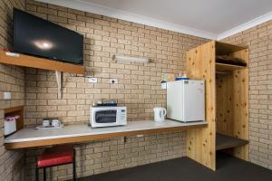 a kitchen with a counter with a microwave and a refrigerator at Allamar Motel in Mount Beauty