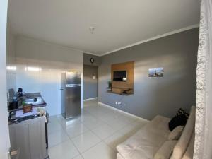 a living room with a white couch and a kitchen at Green House Apartamentos in Ubá