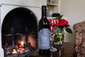 a bottle of wine sitting on a table next to a fireplace at Alice's Cottages in Launceston