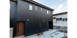 czarny budynek z drewnianymi drzwiami i ławką w obiekcie YUFU-INN - MATSU SUITE - Vacation STAY 95157 w mieście Yufu