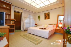 Un dormitorio con una cama blanca y un televisor. en My Friend's Homestay, en Taitung