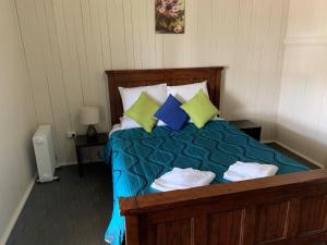 a bedroom with a bed with blue and green pillows at Exchange Hotel Toogoolawah in Toogoolawah