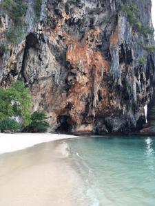 a beach in front of a rocky cliff at Railay Village Resort-SHA Extra Plus in Railay Beach