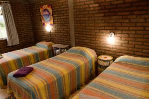 Habitación con 3 camas y pared de ladrillo en La Argentina Complejo en Villa Ciudad de América