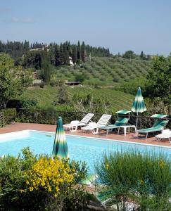 a patio area with a pool and lawn chairs at Hotel Villa Belvedere in San Gimignano