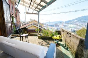 Guest House Nagasaki 2 御船蔵の我が家 2 في ناغاساكي: أريكة على شرفة مطلة على المدينة