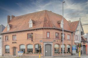 a large red brick building with a brown roof at Anna's Place in Waregem