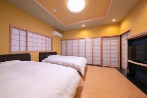 a bedroom with two beds and a flat screen tv at Yufuin Hoteiya in Yufuin