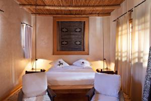 a bedroom with a bed with two chairs and a window at Riad Chbanate in Essaouira