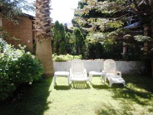 two white chairs sitting on the grass in a yard at Las Araucarias in Pinamar