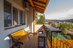 a balcony with a bench and tables on a balcony at Tarno Guest House in Veliko Tŭrnovo