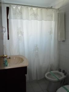 a bathroom with a white shower curtain and a toilet at Las Araucarias in Pinamar