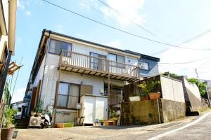 een wit huis met een balkon in een straat bij 渡邊民泊 in Nagasaki