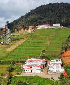 a large house on a hill in a field at Berry Hills Resort in Ooty