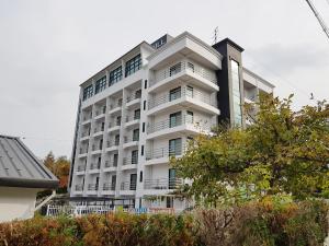 een wit appartementencomplex met balkons en bomen bij Goodstay Motel Hill in Gangneung