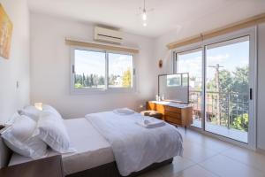 a white bedroom with a bed and a window at Silver Apartment 3 in Limassol