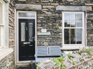 ボウネス・オン・ウィンダミアにあるLittle Brook Cottageの黒い扉と窓のある石造りの家