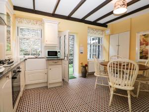 ボウネス・オン・ウィンダミアにあるLittle Brook Cottageの白いキャビネット、テーブルと椅子付きのキッチンが備わります。
