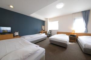a hotel room with three beds and a tv at Heiwadai Hotel 5 in Fukuoka