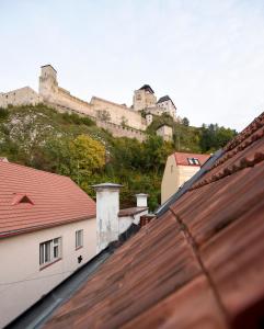 a castle on top of a hill with roofs at Apartmán s átriom v historickom centre in Trenčín