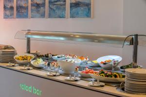 a buffet line with bowls and plates of food at Faros Hotel Ayia Napa in Ayia Napa