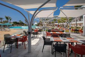 a restaurant with tables and chairs and a pool at Faros Hotel Ayia Napa in Ayia Napa
