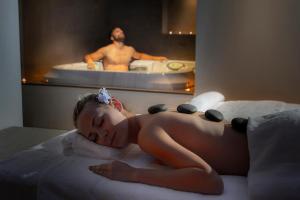 a woman laying on a bed with a man in a bath tub at Faros Hotel Ayia Napa in Ayia Napa
