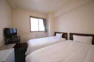 a room with two beds and a television in it at Heiwadai Hotel Arato in Fukuoka