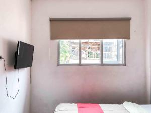 ein Schlafzimmer mit einem Fenster, einem Bett und einem TV in der Unterkunft RedDoorz near Eco Green Park Batu in Batu