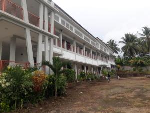 un grand bâtiment blanc avec des palmiers devant lui dans l'établissement KoolKost At Malalayang Manado Minimum Stay 6 Nights, à Malalayang