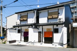 biały budynek z czarnymi drzwiami i oknami w obiekcie Kyotoya Tsukinoyu Kagayakitei North w mieście Kioto