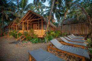 a row of lounge chairs in front of a resort at Goa Cottages Agonda in Agonda