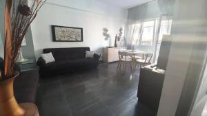 a living room with a black couch and a table at City Center Comfortable Studio Apartment in Kavála