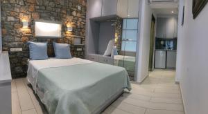 a bedroom with a bed and a stone wall at Azzurro in Skiathos Town