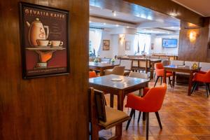 a restaurant with tables and chairs and a sign on a wall at Hotel La Dolce Vita in Zărneşti