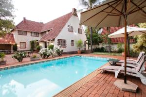 a swimming pool with two chairs and an umbrella at Brooklyn Manor in Pretoria
