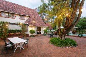 un patio con mesa y sillas frente a una casa en Brooklyn Manor en Pretoria